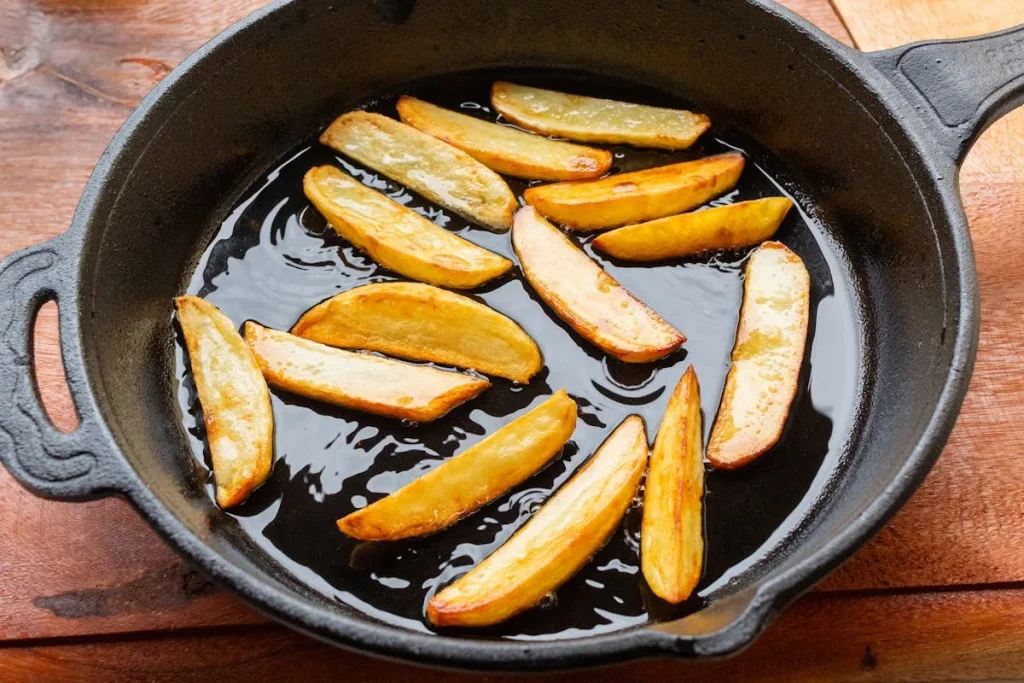 Cast iron skillet with golden potato wedges cooking