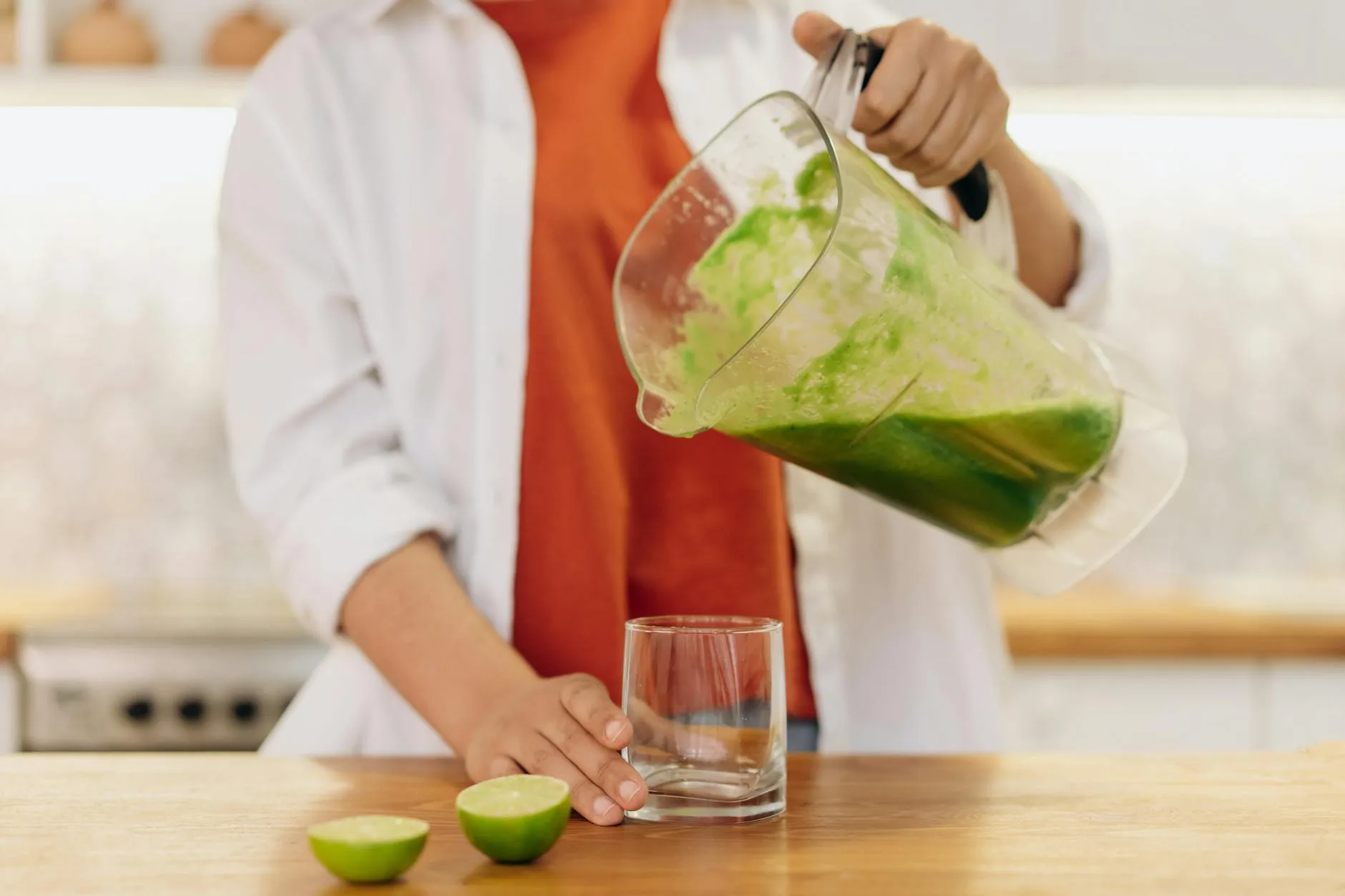 Pouring a freshly blended green smoothie from a blender into a glass