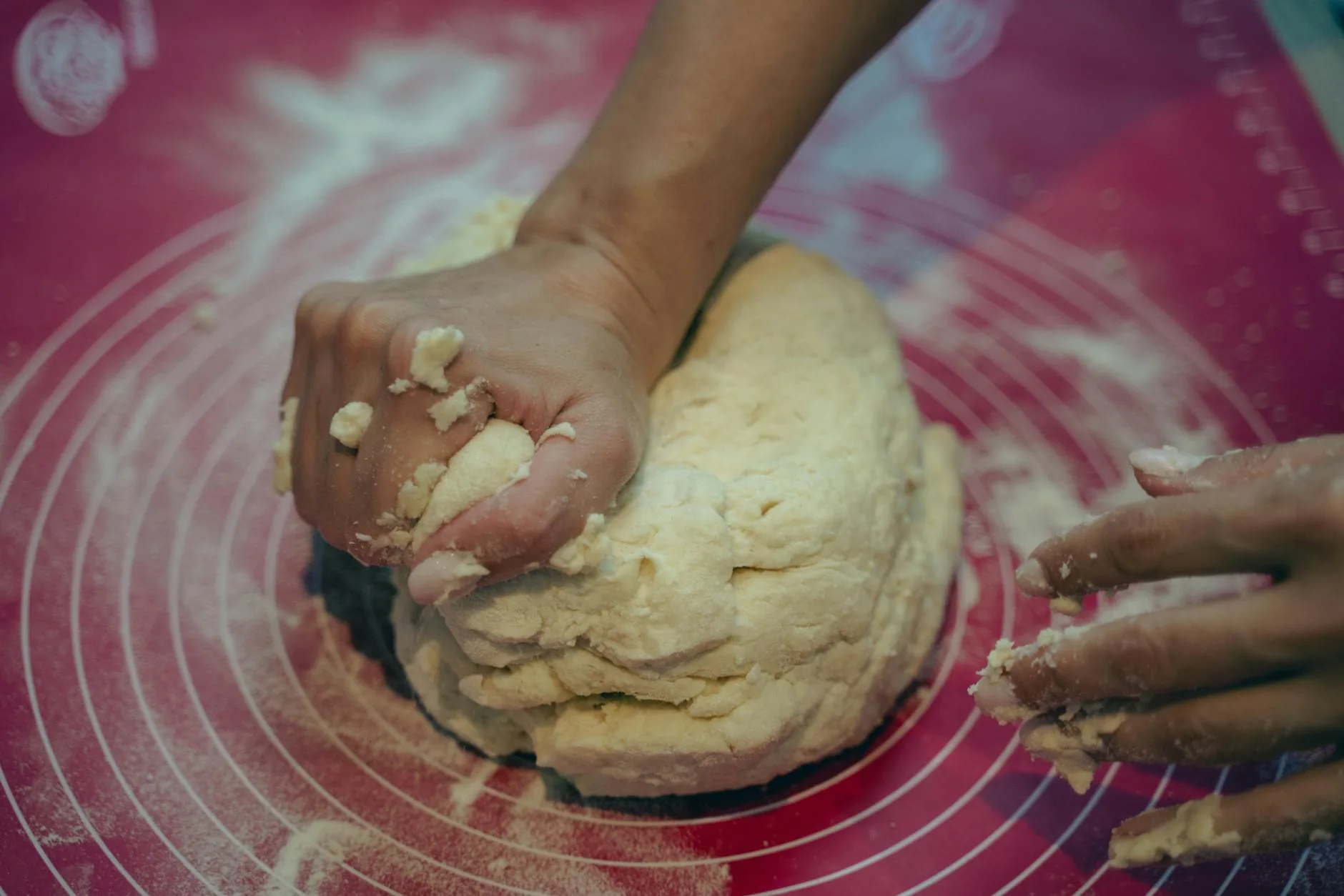 Bread dough being kneaded with flour on a kitchen counter