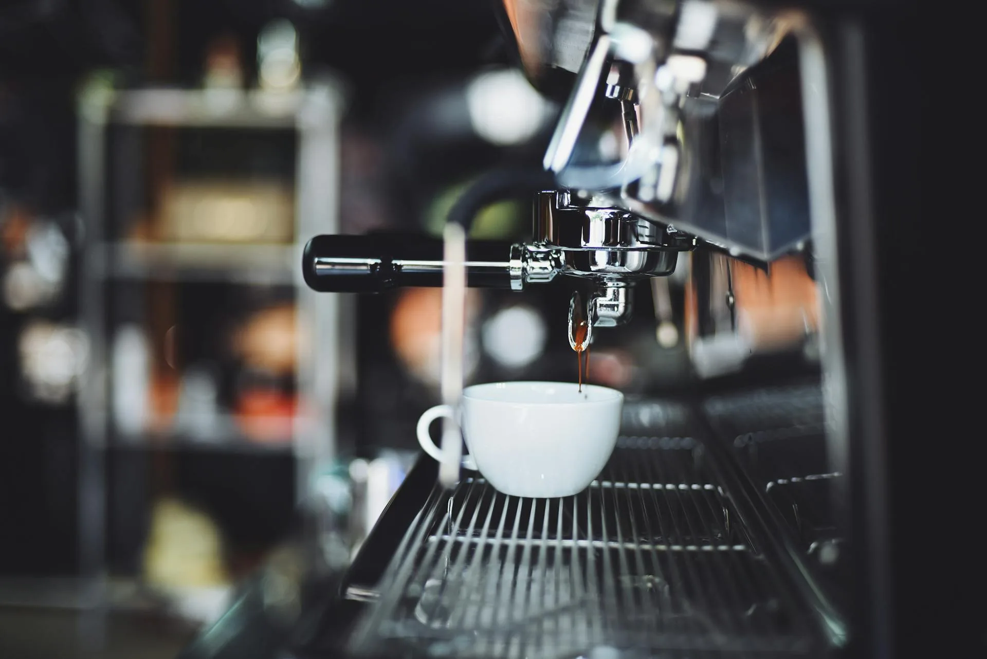 Espresso machine extracting coffee into a small white cup with rich dark crema