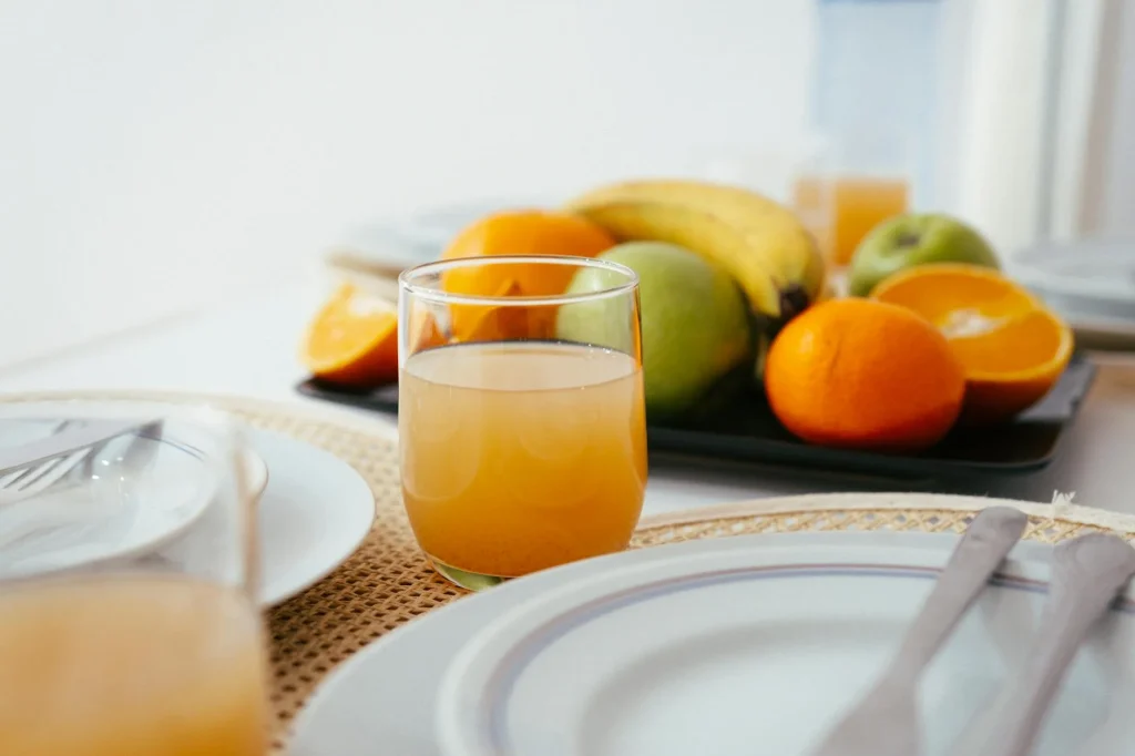 Fresh green juice in a glass surrounded by fruits and vegetables