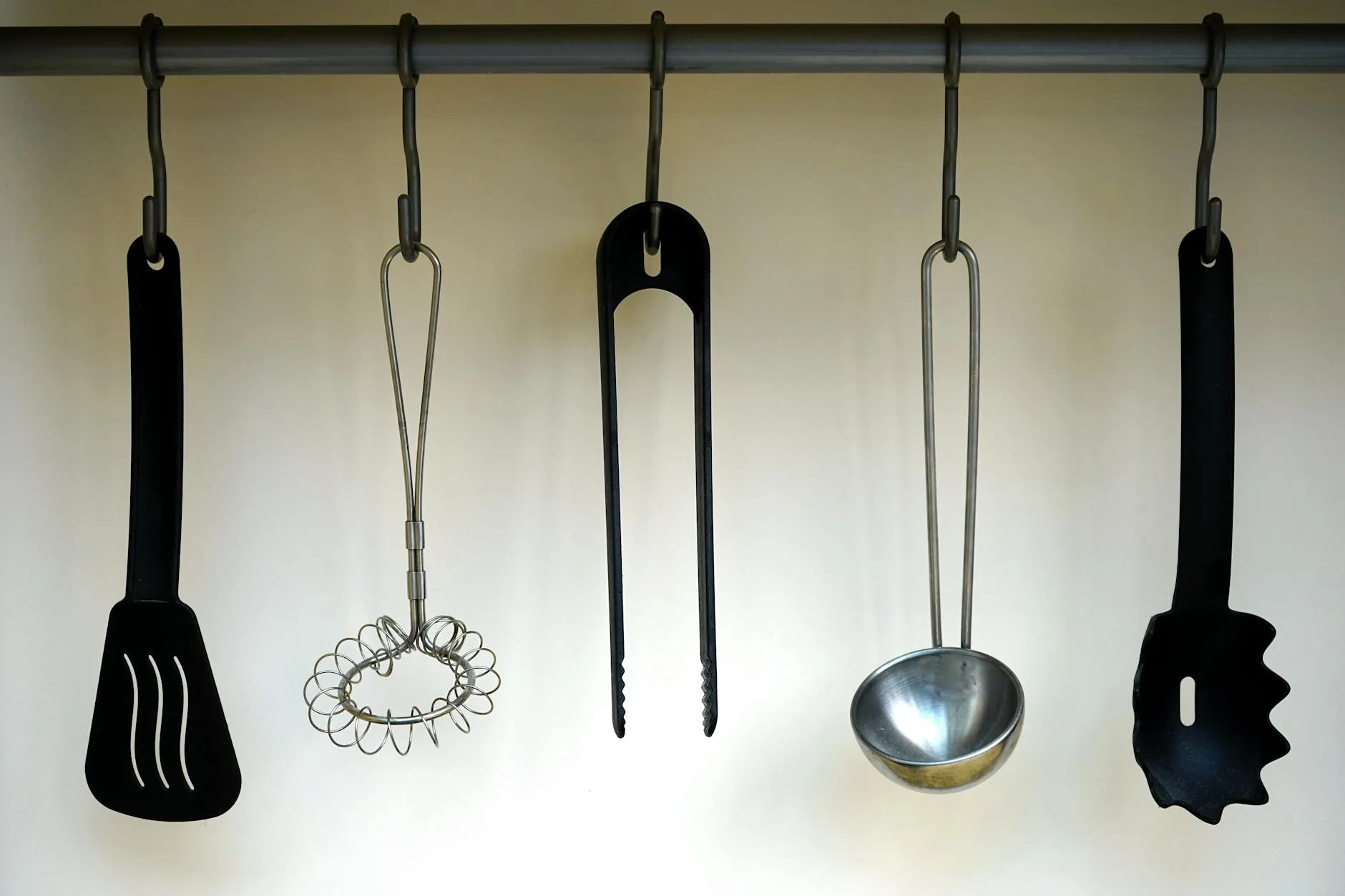 Kitchen wall with hanging utensils on hooks for storage