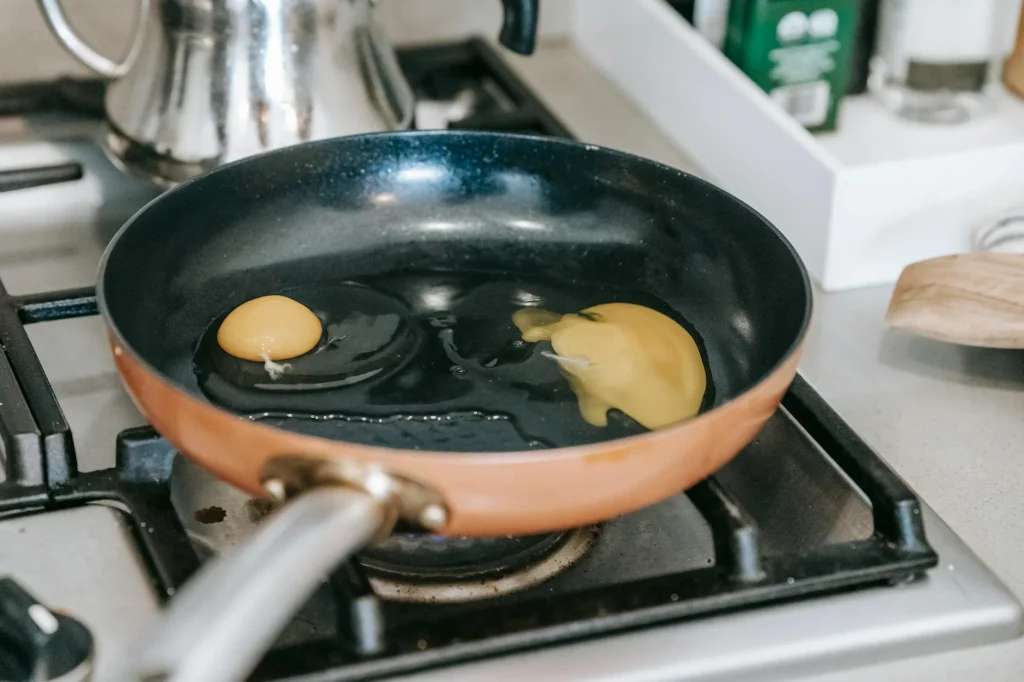 Eggs cooking in a non-stick frying pan on a hob