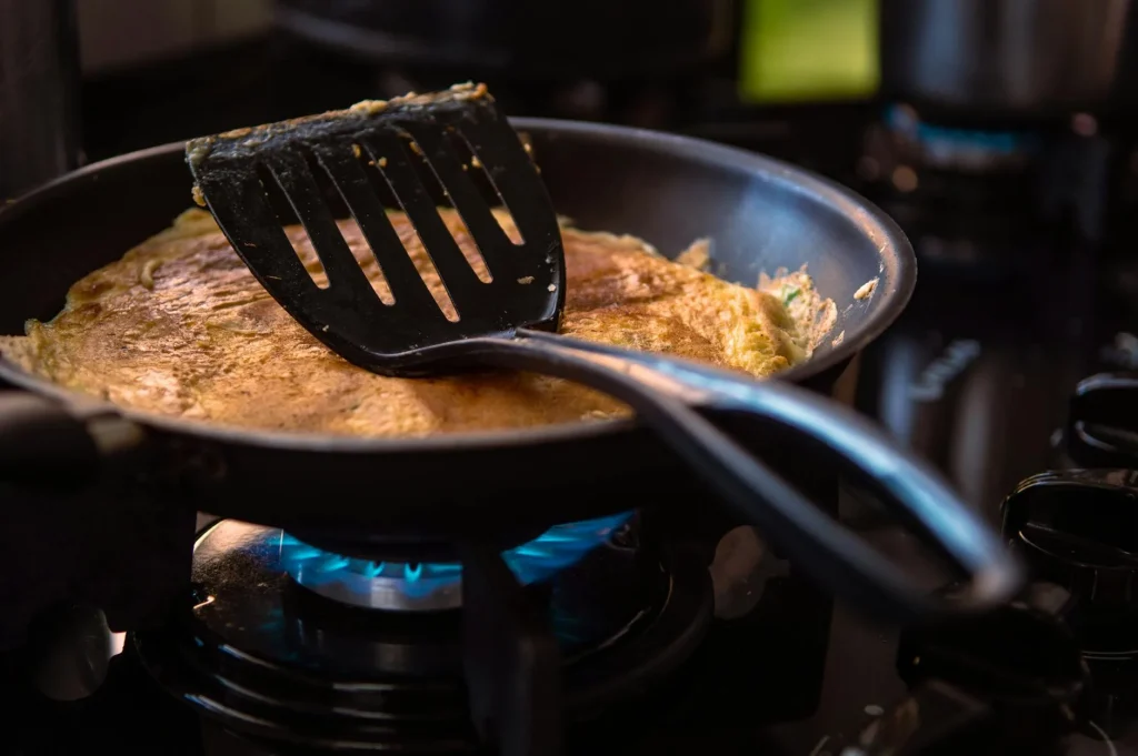 Eggs cooking in a non-stick frying pan on a gas hob