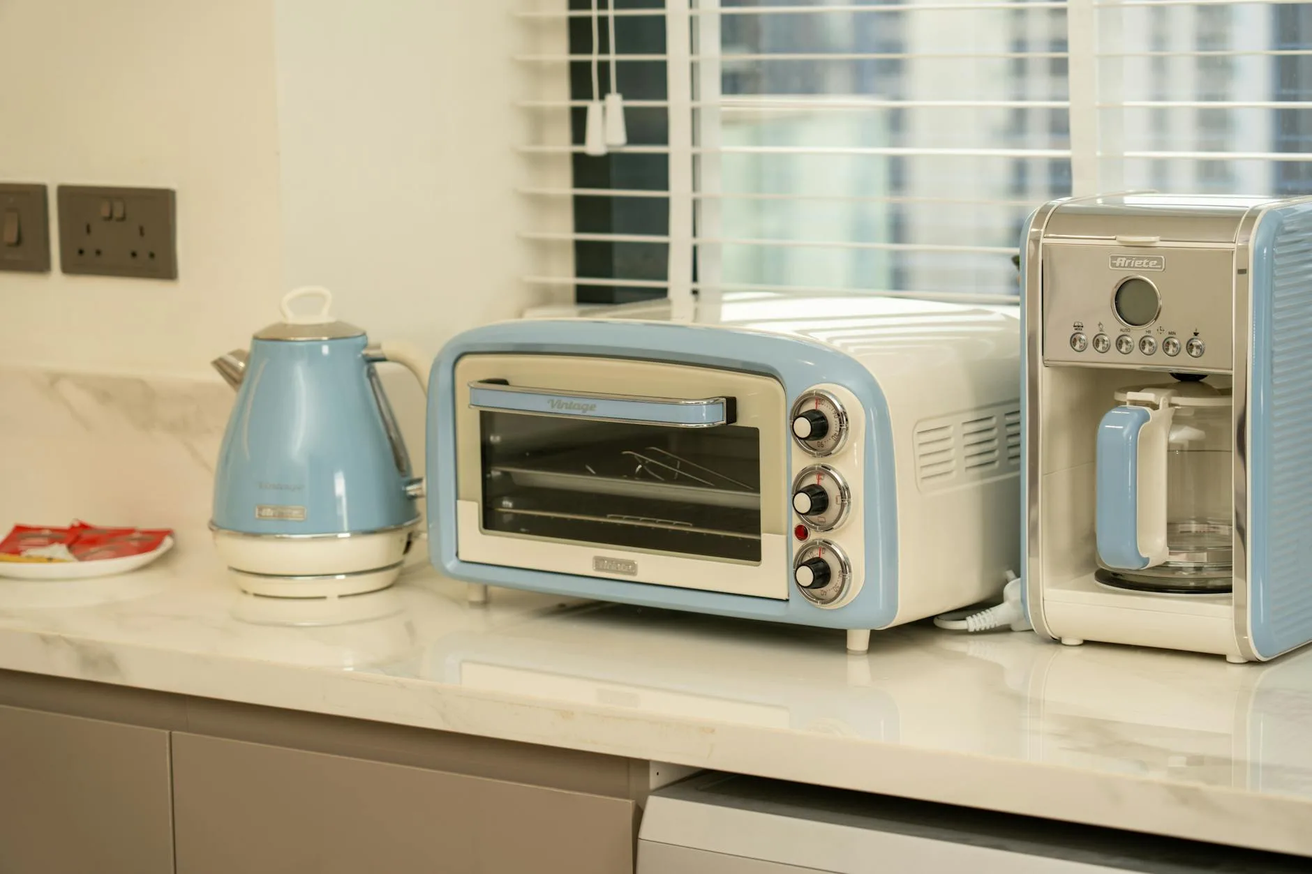 Retro-style kitchen appliances in pastel colours on a countertop