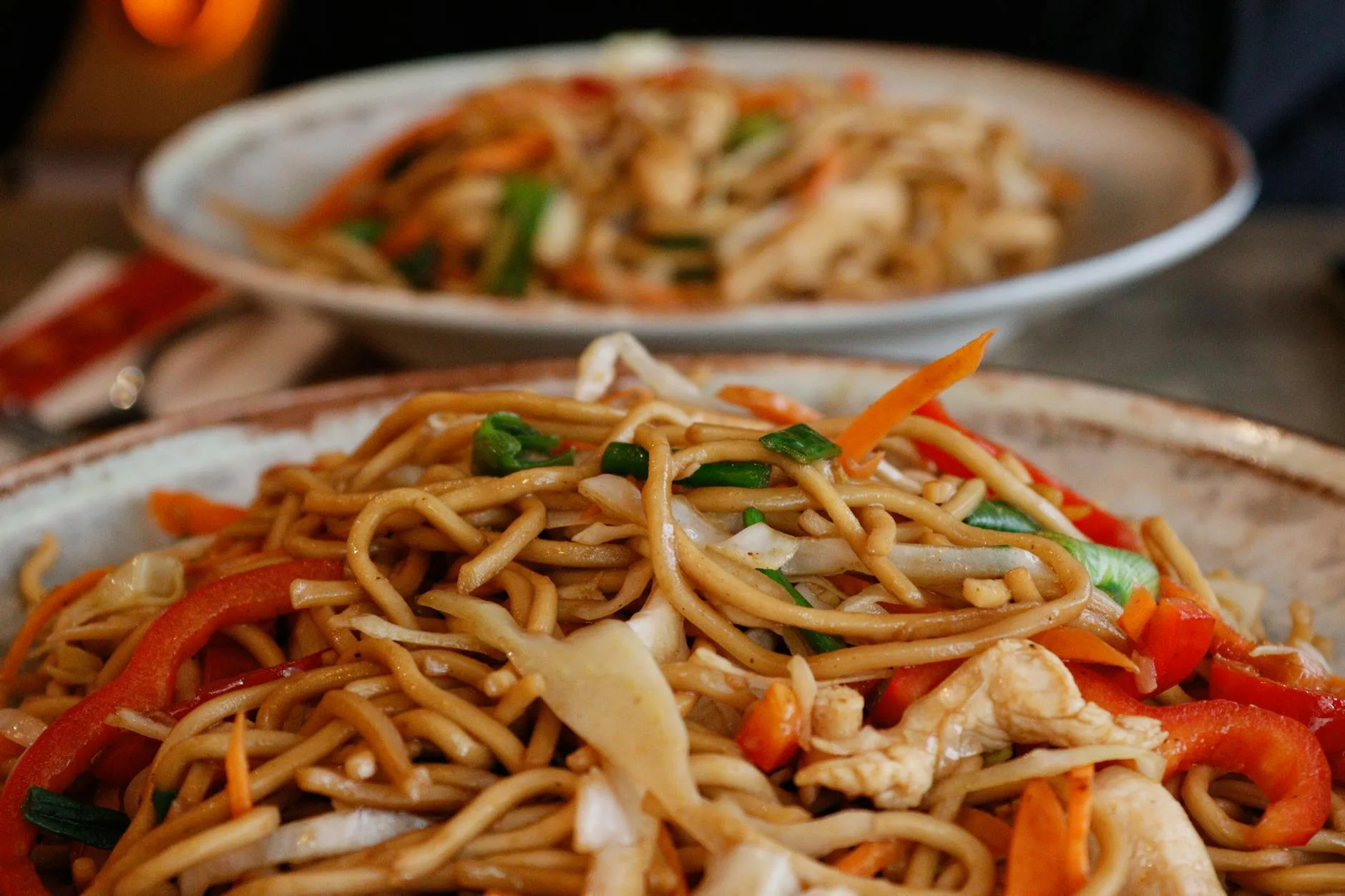 Stir-fry noodles being cooked in a wok with chopsticks