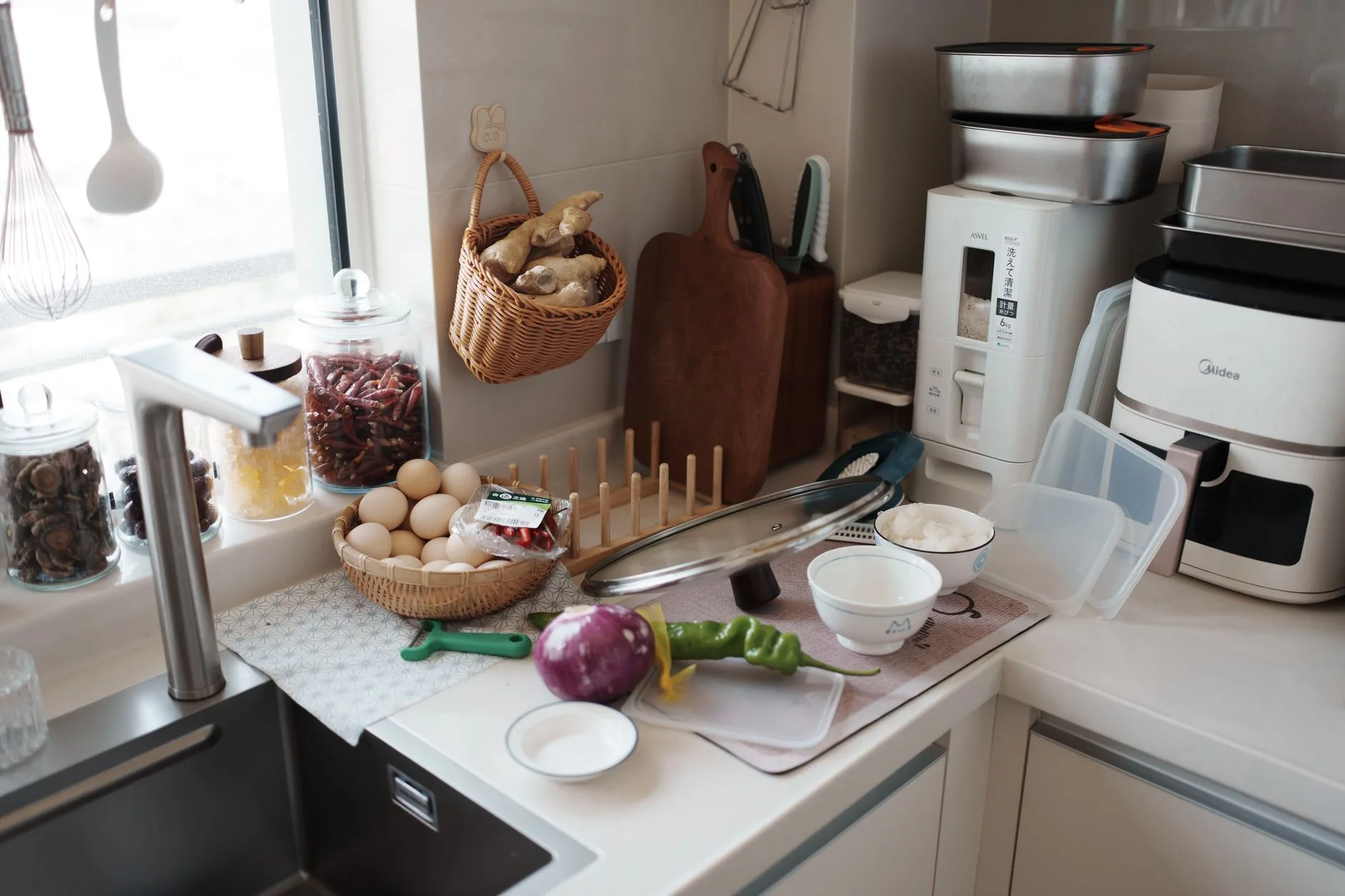White air fryer on a kitchen counter beside everyday cooking ingredients