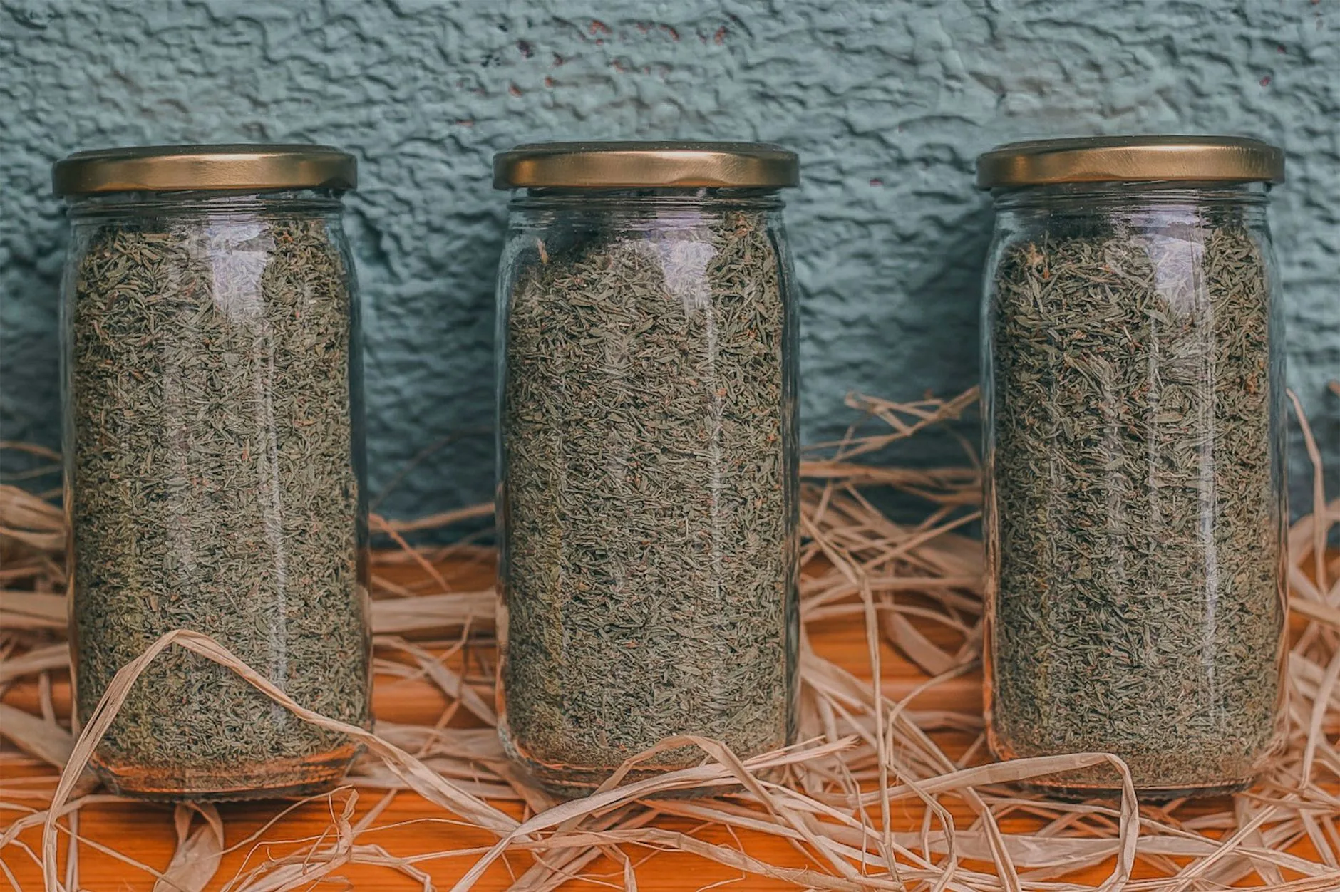 Dried herbs stored in labelled jars on a kitchen shelf