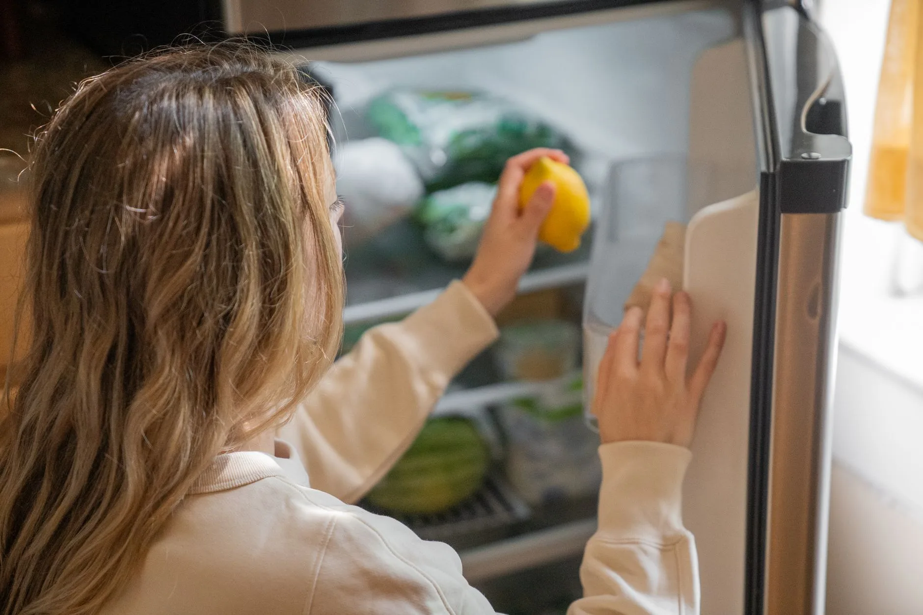 Person reaching into a home fridge during meal prep